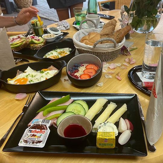 Frühstückstisch mit Gebäck, Spiegelei und Gemüse